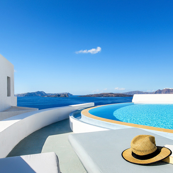 Grand Ambassador infinity pool with sea view, straw hat, sunglasses, and book