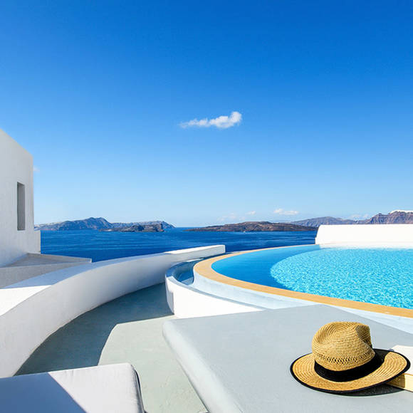 Grand Ambassador infinity pool with sea view, straw hat, sunglasses, and book