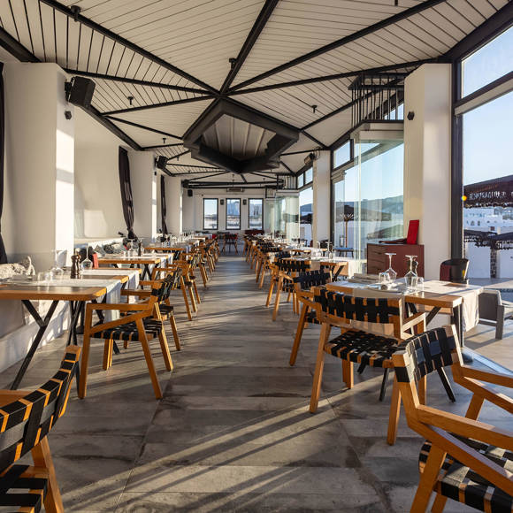 Grand Ambassador Dione restaurant bright, spacious dining area with modern wooden chairs and pool view