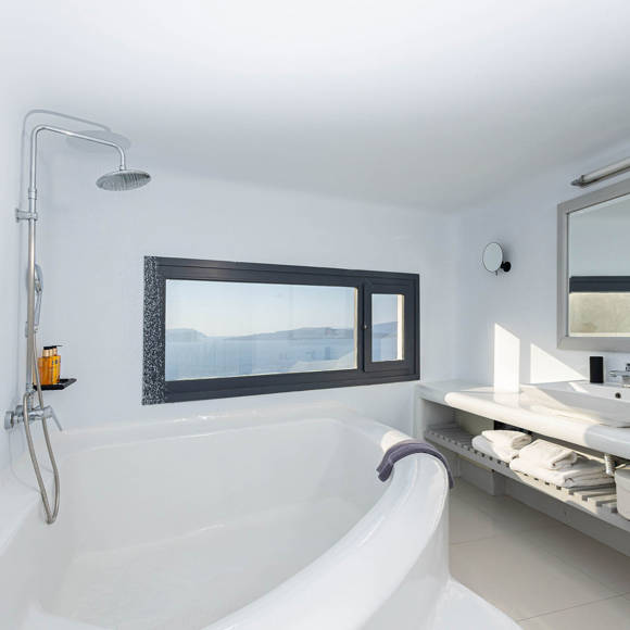 Grand Ambassador Santorini Serenity Two Bedroom Suite bathroom with built-in tub, rainfall shower, and window with sea view