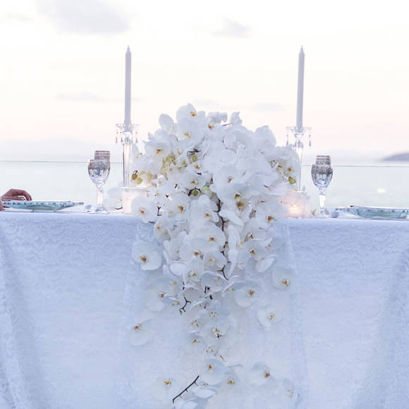 Grand Ambassador wedding venue elegant private dinner with bride and groom at a table decorated with white orchids overlooking the sea