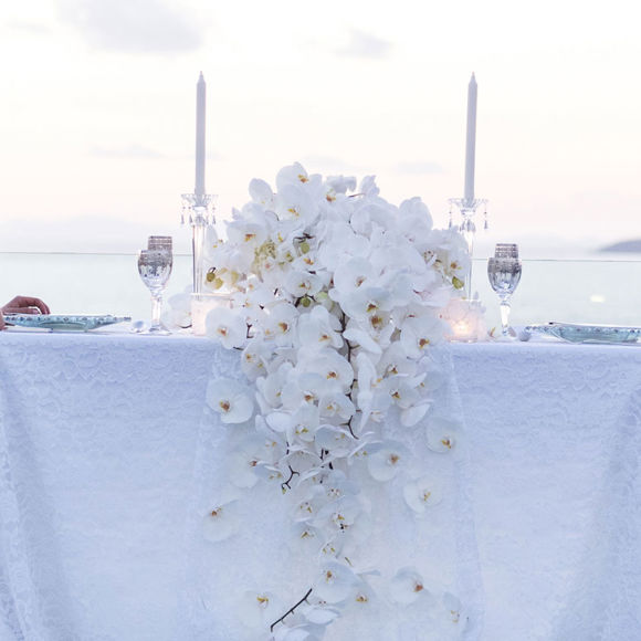 Grand Ambassador wedding venue elegant private dinner with bride and groom at a table decorated with white orchids overlooking the sea