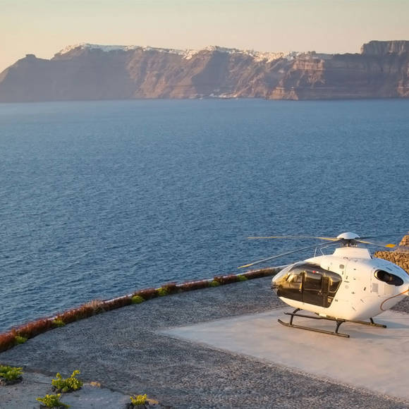Helicopter on helipad overlooking sea and cliffs at Grand Ambassador hotel during sunset