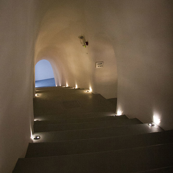 Dimly lit curved staircase with small recessed lights at Grand Ambassador Hotel