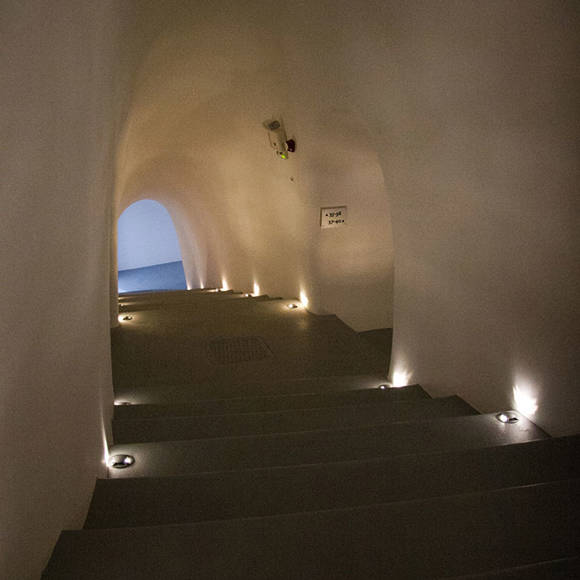 Dimly lit curved staircase with small recessed lights at Grand Ambassador Hotel