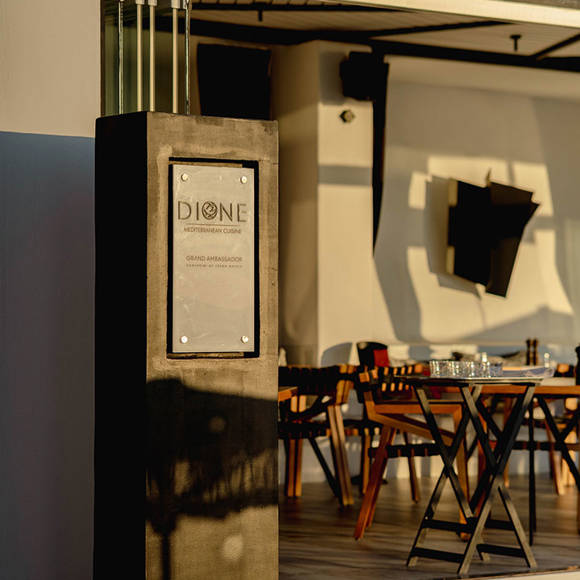 Grand Ambassador Dione restaurant entrance sign and modern dining area in afternoon light