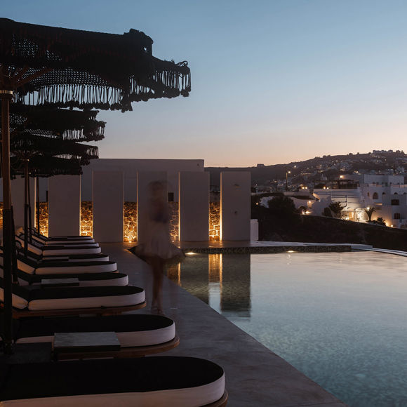 Grand Ambassador pool bar evening scene with pool, sunbeds, parasols, and illuminated hillside village