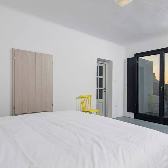 Grand Ambassador Santorini Villa guest bedroom with double bed, built-in wardrobe, and panoramic windows