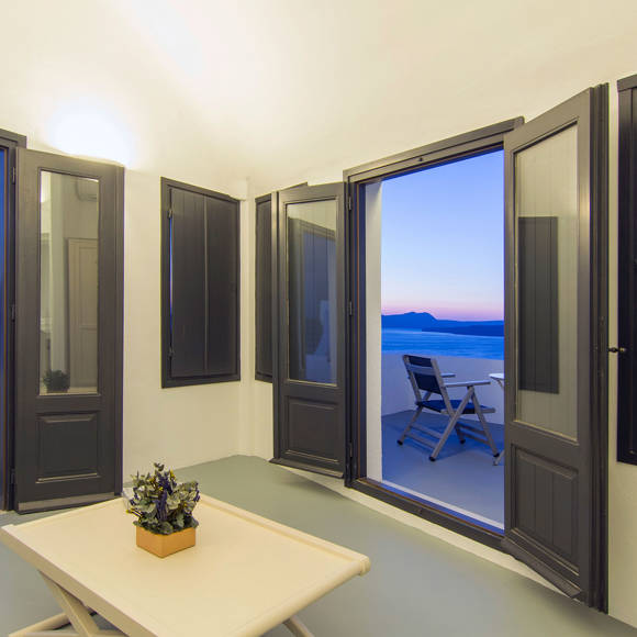 Grand Ambassador Santorini Serenity Two Bedroom Suite living area with open terrace, panoramic caldera and sea views at dusk