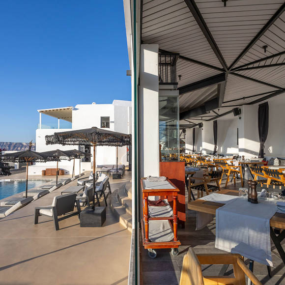 Grand Ambassador Dione restaurant panoramic view of indoor dining and outdoor poolside lounge area with umbrellas