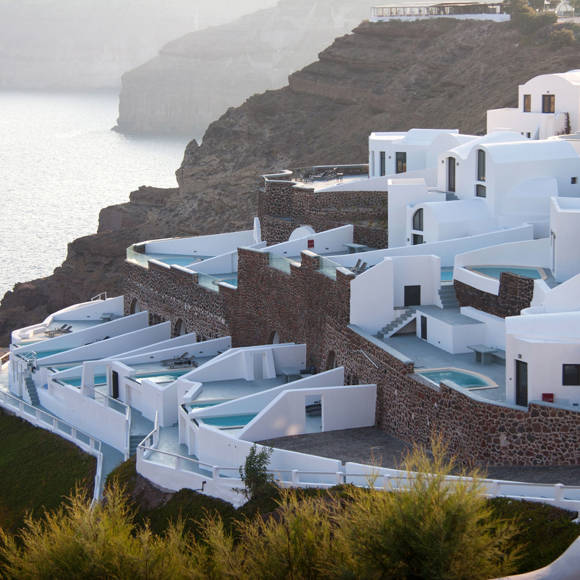 Cliffside view of Grand Ambassador Hotel with white villas and private pools overlooking the sea