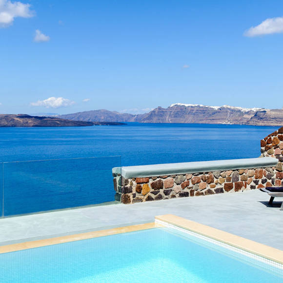 Poolside terrace with lounge chairs overlooking calm blue sea and distant islands under a bright sky