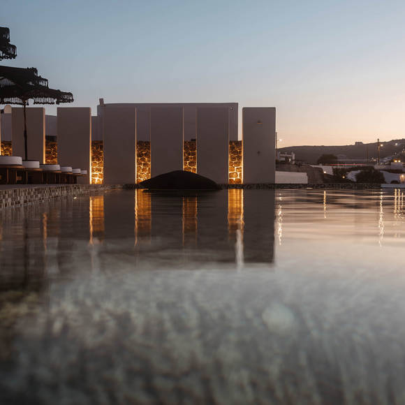Grand Ambassador pool bar sunset view with illuminated pool, cushioned sunbeds, and parasols