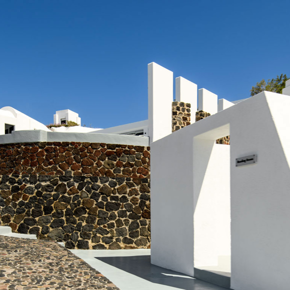 Exterior view of Grand Ambassador hotel with white buildings and stone walls under a clear blue sky