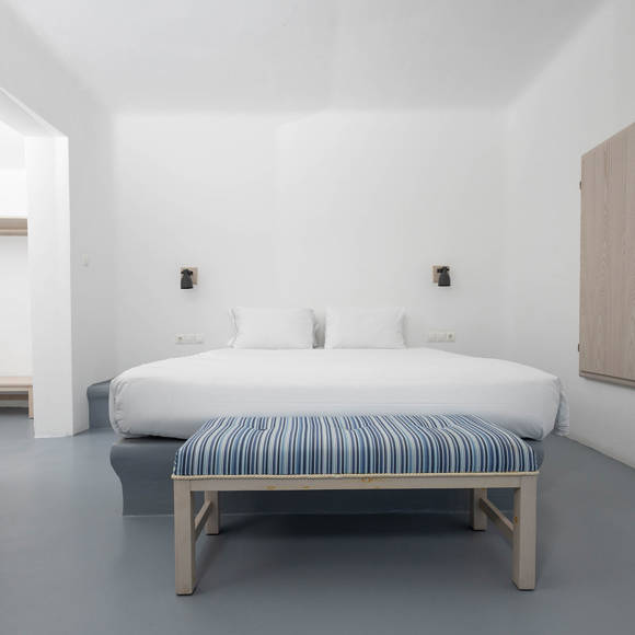 Grand Ambassador Santorini Serenity Two Bedroom Suite bedroom with double bed, striped bench, and minimalist Cycladic design