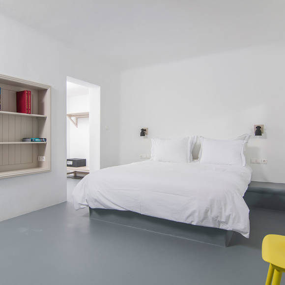 Grand Ambassador Santorini Serenity Two Bedroom Suite minimalist bedroom with double bed, built-in shelf, and yellow accent chair