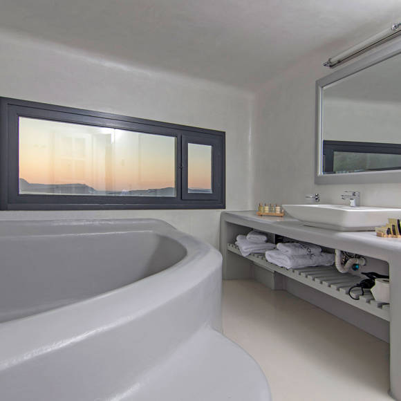 Grand Ambassador Santorini Villa luxury bathroom with built-in tub, twin sinks, and sea view at sunset
