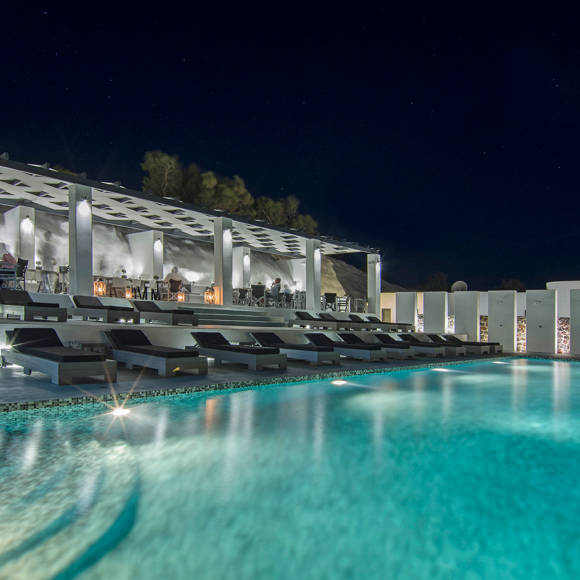 Grand Ambassador swimming pool illuminated at night with modern sunbeds and open-air restaurant