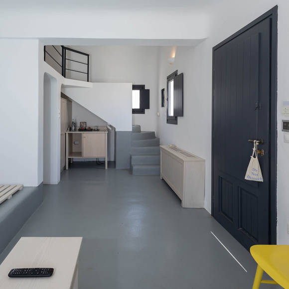 Grand Ambassador Santorini Petit Suite entrance hall with work desk, yellow chair, and minimalist Cycladic decor
