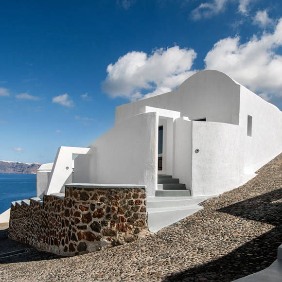 Whitewashed pathway and traditional architecture at Grand Ambassador hotel with a clear blue sky and sea in the background