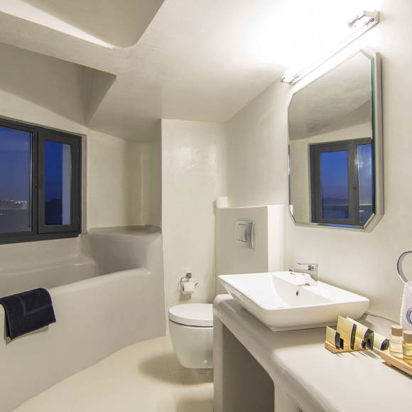 Grand Ambassador Santorini Serenity Two Bedroom Suite bathroom with Cycladic built-in tub, luxury amenities, and panoramic window