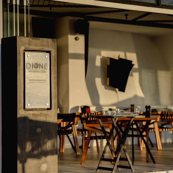 Grand Ambassador Dione restaurant entrance with Mediterranean cuisine sign and modern dining tables