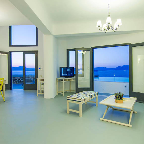 Grand Ambassador Santorini Villa spacious living and dining area with caldera view, yellow chairs, and modern Cycladic decor