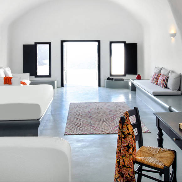 Grand Ambassador Santorini Infinity Cave Suite elegant bedroom with arched ceilings and ambient lighting